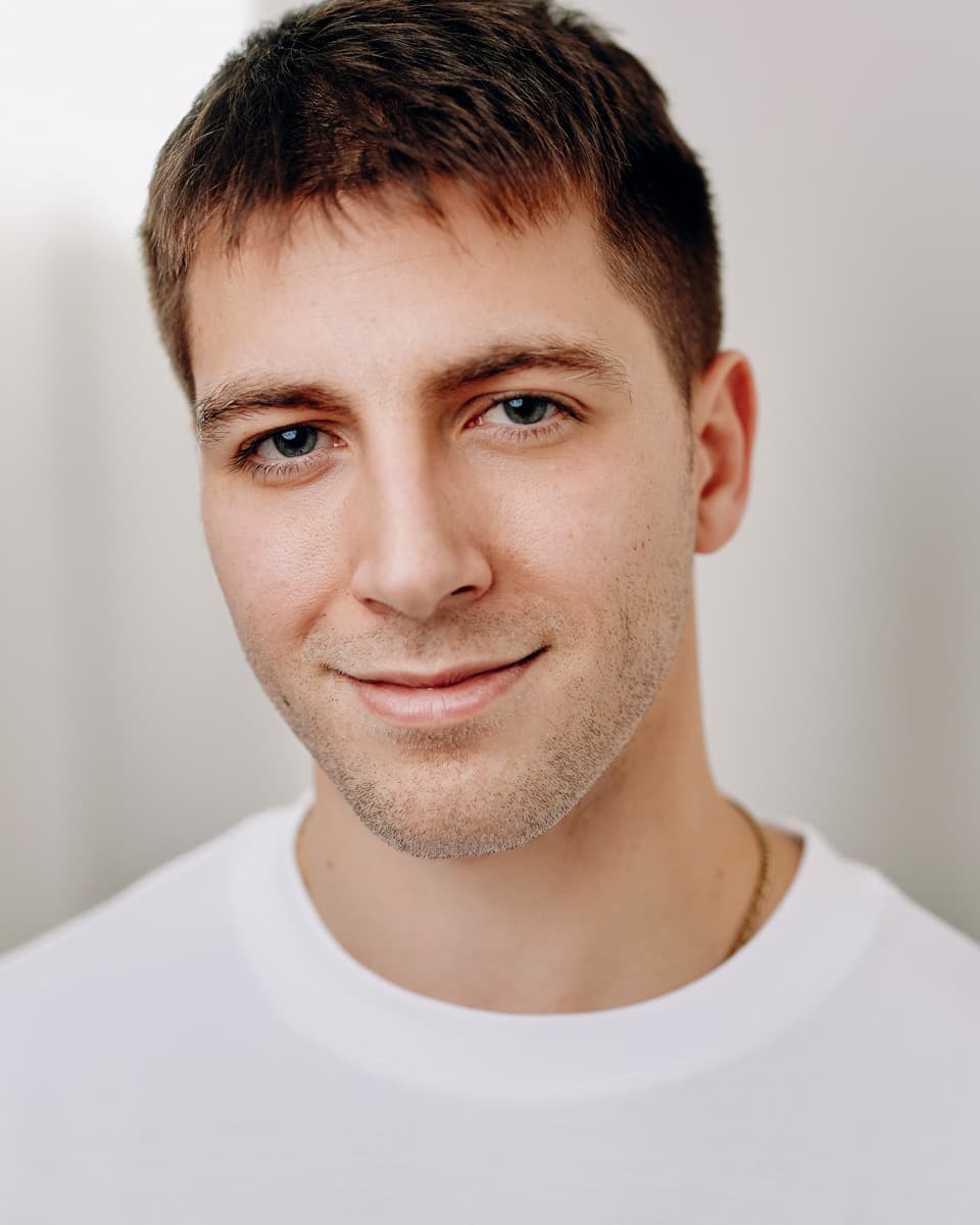 Actor commercial headshot wearing a white sweater with warm studio tones