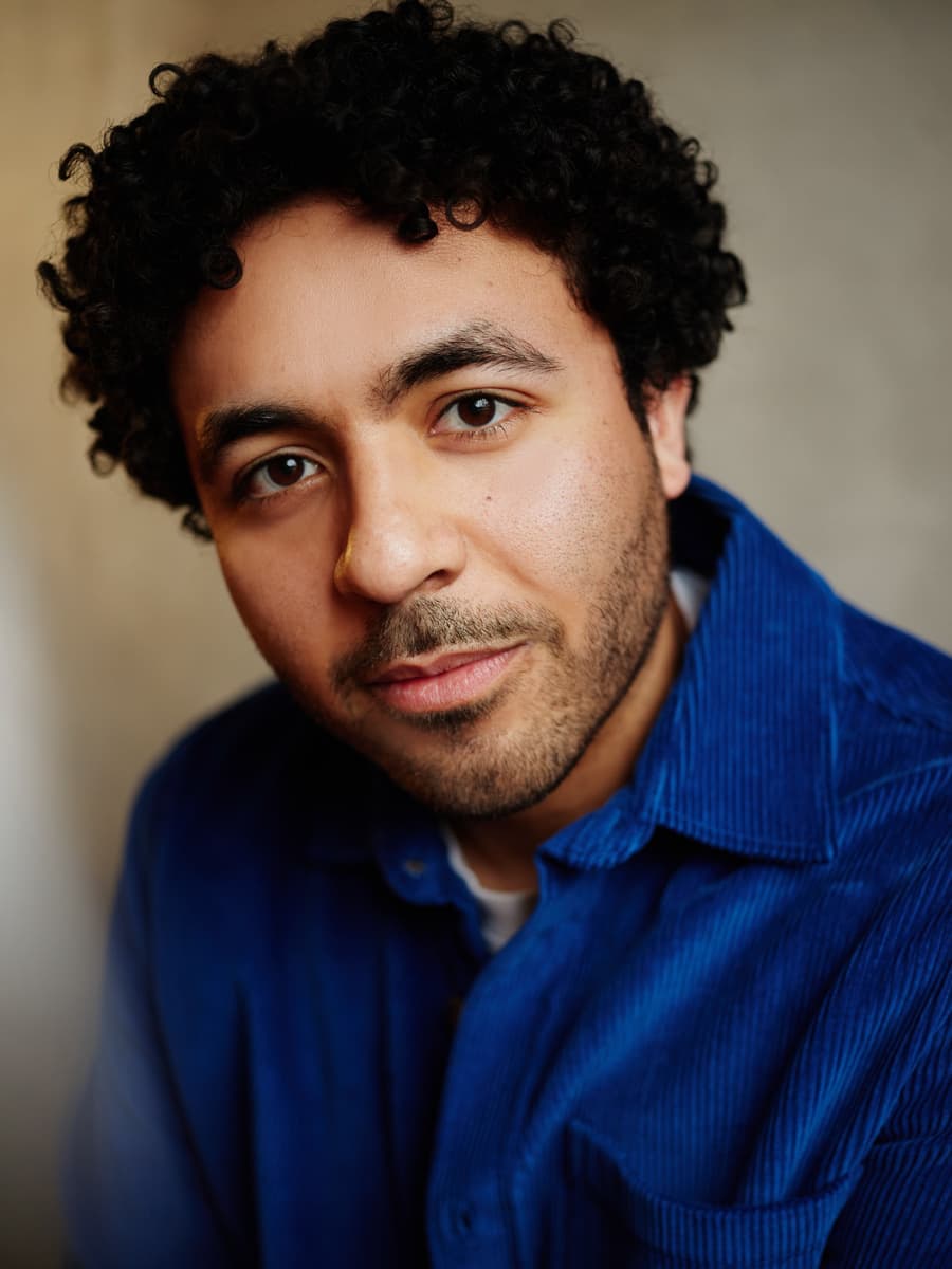 Theatrical headshot of a bearded actor with an intense and commanding expression against a studio background