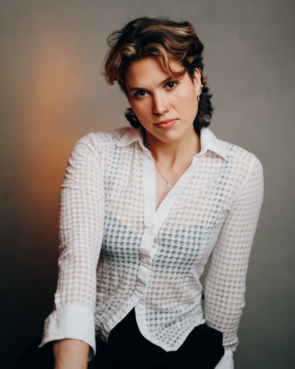 Toronto actress studio portrait of a woman with short wavy brown hair and a nose ring in a sheer houndstooth blouse, with a direct self-assured look