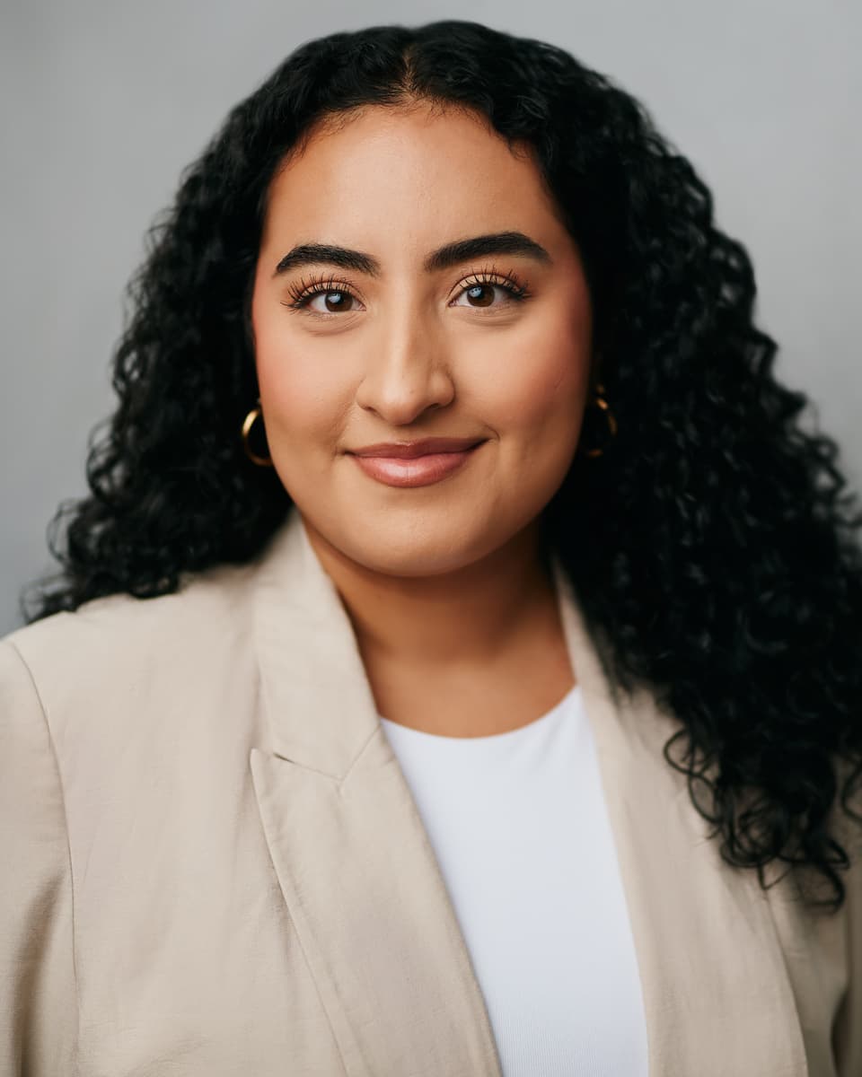 Toronto professional headshot of a woman in a layered warm-toned blazer with a composed and confident expression against a studio backdrop